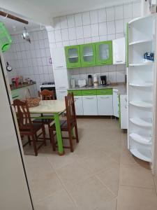 a kitchen with a table and chairs and green cabinets at Casa de Campo com piscina in Mairinque