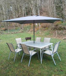 a table with chairs and an umbrella on the grass at Maison de campagne in Picherande