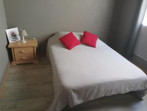a bedroom with a bed with two red pillows on it at Maison de campagne in Picherande