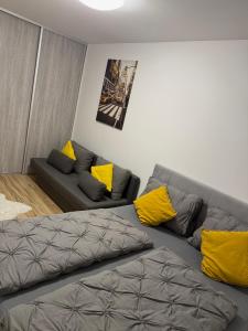 a living room with a gray couch and yellow pillows at Prestige Suite DS in Dunajská Streda