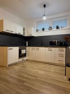 a kitchen with white cabinets and a wooden floor at Prestige Suite DS in Dunajská Streda