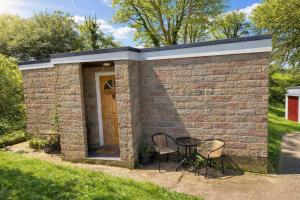a small brick building with a table and chairs at Hillside Chalet in Kilkhampton +5 photos