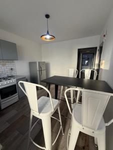 a kitchen with a black table and white chairs at Aloha II in Rosario