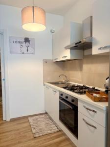 a kitchen with white cabinets and a stove top oven at Monolocale elegante e luminoso nel Centro Storico- A due passi da tutto in Pordenone