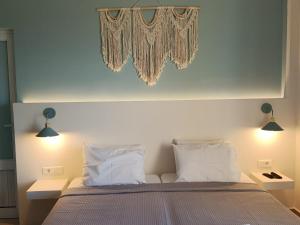 a bedroom with a bed with white pillows and two lights at Liros in Kamiros
