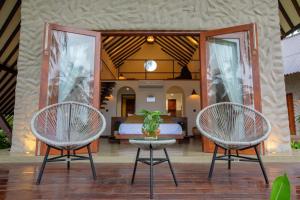 two chairs and a bed in a bedroom at Avora Lake Villas in Anuradhapura