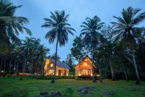 a house in a field with palm trees at Avora Lake Villas in Anuradhapura