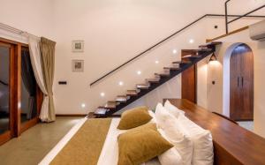 a bedroom with a bed with pillows and a staircase at Avora Lake Villas in Anuradhapura