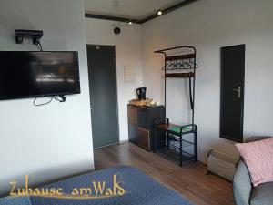 a living room with a flat screen tv and a shelf at Zuhause Am Wald in Brilon +64 photos