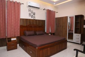a bedroom with a large wooden bed with red curtains at Aashray in Dehradun