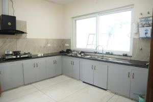a kitchen with white cabinets and a large window at Aashray in Dehradun