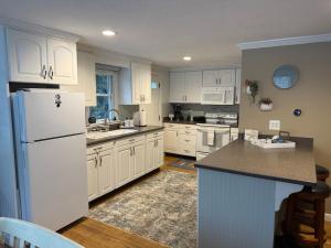 a kitchen with white cabinets and a white refrigerator at Cape Lake Private Beach Fire Table in Plymouth