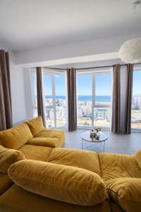 a living room with a yellow couch and large windows at Apartament Meraki SeaView in Mamaia Sat/Năvodari +2 photos