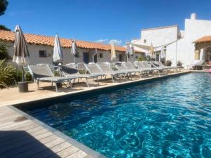 a pool with chairs and umbrellas next to a building at Hôtel du Pont Blanc in Saintes-Maries-de-la-Mer