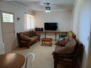 a living room with two couches and a flat screen tv at Casa de Campo com piscina in Mairinque