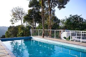 a swimming pool with a white fence around it at Misty Bean Resort in Meppādi +24 photos