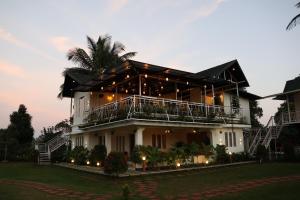 a large white building with a balcony and a palm tree at Misty Bean Resort in Meppādi
