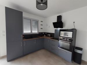 a kitchen with gray cabinets and a stove and microwave at Maison Saint-Pardoux in Friaudour