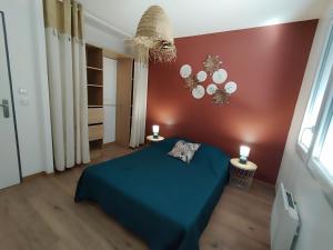 a bedroom with a blue bed and a red wall at Maison Saint-Pardoux in Friaudour