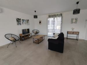 a living room with a black couch and a tv at Maison Saint-Pardoux in Friaudour