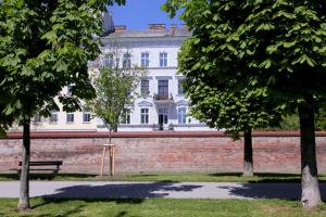 a white building with a brick wall and two trees at Casa Nostra - Helle Wohnung - direkt am Augarten in Vienna