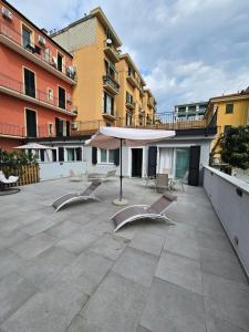 a patio with chairs and an umbrella and buildings at Case di Daniela in Chiavari