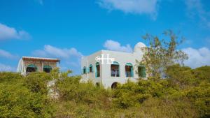 a white building on top of a hill with trees at Kavunjeni Villa in Uyombo