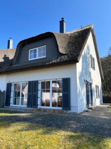 an old white house with a thatched roof at Wellenläufer Breege in Breege