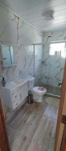 a white bathroom with a sink and a toilet at Chalé da Helô in Nova Friburgo