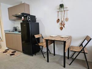 a kitchen with a black refrigerator and a wooden table at BE Residences Lahug in Cebu City