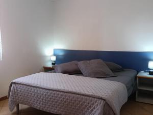 a bedroom with a bed with a blue headboard at LES BULLES DE MONA - Marina Corse - 2 ch - Clim - Terrasse-pieds dans leau-plage in Ghisonaccia