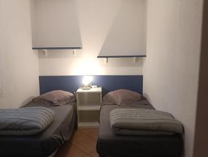 a room with two beds and a night stand with a lamp at LES BULLES DE MONA - Marina Corse - 2 ch - Clim - Terrasse-pieds dans leau-plage in Ghisonaccia