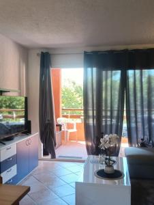 a living room with a couch and a table with flowers at LES BULLES DE MONA - Marina Corse - 2 ch - Clim - Terrasse-pieds dans leau-plage in Ghisonaccia