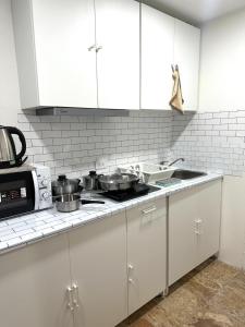a kitchen with white cabinets and a stove with pots and pans at Brand new furnished studio Apartment near old Town in Phuket