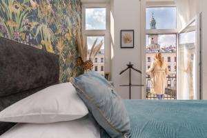 a bedroom with a bed and a woman looking out the window at V62 studio apartments- Downtown Sopron in Sopron