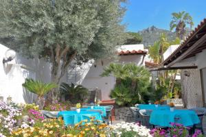 a patio with blue tables and chairs in a garden at Hotel Casa Cigliano in Forio d'Ischia