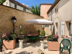 a patio with a table and chairs and an umbrella at Chateau de Plombières Maison Gauthier Dijon in Plombières-lès-Dijon