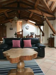 a living room with a black couch and a wooden table at Violette in Bazus +1 photo