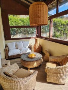 a living room with wicker chairs and a table and a couch at Une histoire à écrire in Belleville-sur-Saône