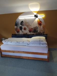 a bedroom with a bed with a flower mural on the wall at Kleines Haus am Wald in Rohrbach
