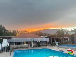 a house with a swimming pool in front of a sunset at Isabella Hostel and Pool in Alto Boquete