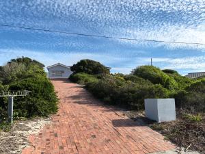 a brick pathway leading to a house with a blue sky at The Lookout in Pearly Beach