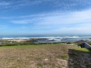 a view of the ocean from a hill with a grass field at The Lookout in Pearly Beach