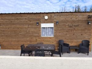 a table and chairs in front of a wooden wall at La jonquiere etablisement climatisé in Landouzy-la-Cour