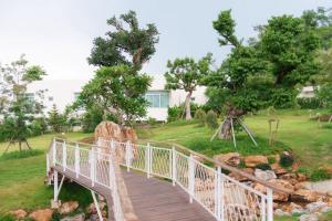a wooden bridge over a garden with trees and rocks at The Peak Hill Pool Villa in Ban Wa Kachieo