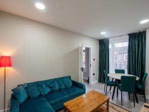 a living room with a blue couch and a table at Spacious 2-Bedroom Flat in Worcester Park