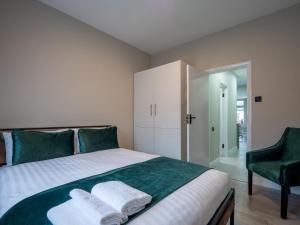 a bedroom with a bed with two towels on it at Spacious 2-Bedroom Flat in Worcester Park