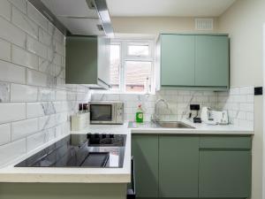 a kitchen with green cabinets and a sink at Spacious 2-Bedroom Flat in Worcester Park