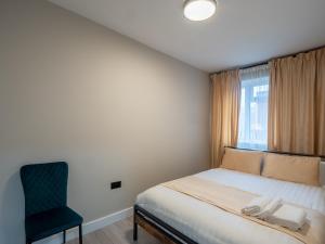 a bedroom with a bed and a chair and a window at Spacious 2-Bedroom Flat in Worcester Park +13 photos