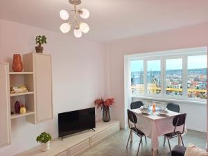 a living room with a table with chairs and a television at Inima Iasului - Central View Apartment in Iaşi